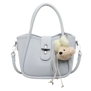 Close-up of light blue lychee pattern bucket bag with a cute plush dog pendant