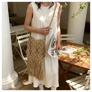 Detail shot of bohemian woven straw bag with hollow diamond patterns and long fringe tassels