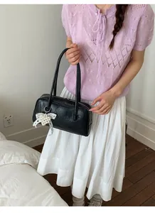 Détail du sac baguette noir plissé en similicuir avec breloque cœur en dentelle