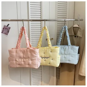 Detailed shot of quilted nylon tote bags in pink, yellow, and blue with pleated handles