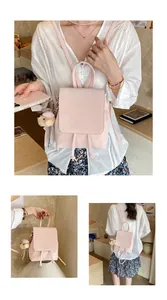 Detail of light pink mini leather backpack with a plush bear charm and drawstring closure