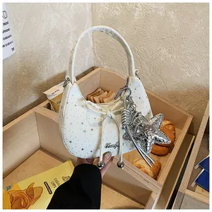 Detail van een witte halve maan tas met zilveren sterrenprint en strikdecoratie