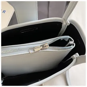 Detailed interior of light blue bucket bag showing zipper compartment and litchi grain leather