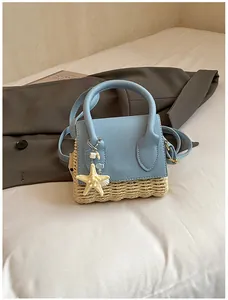Detail of mini straw handbag in light blue and wood color with starfish charm