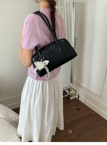 Détail d'un sac sous les bras noir rectangulaire avec charm en perles et dentelle