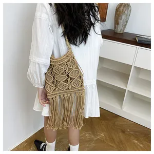 Detail of hand-woven hollow knit pattern and long fringe tassels on khaki straw beach bag