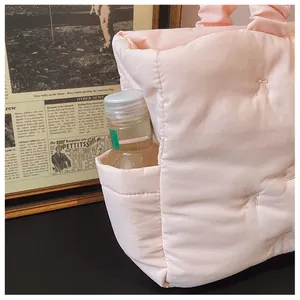 Detail of pink quilted tote bag with side pocket holding a bottle and bow embroidery