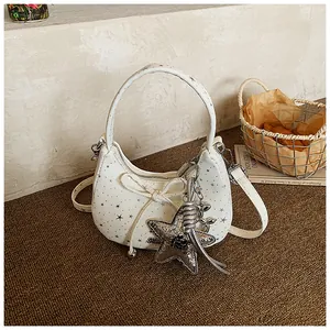 Detail van witte halve maan tas met sterrenpatroon, decoratieve strik en sterhanger