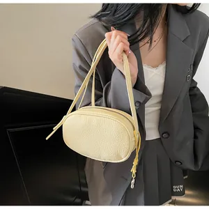 Detail of a creamy beige pillow bag with natural leather texture on a model's shoulder