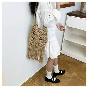 Detail of bohemian woven tassel shoulder bag featuring diamond hollow patterns on a model