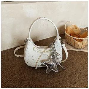 Detail van witte hobo-tas met zilveren sterhanger en een verfijnde decoratieve strik