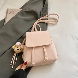 Detalle de la mochila de cuero rosa con cierre de cordón y adorable colgante de perro
