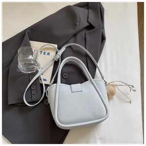 Detailed top view of a grey-blue lychee pattern bucket bag with pompom charm accessory
