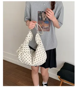 Close-up of beige polka dot hobo bag showing drawstring pleats and side bow details