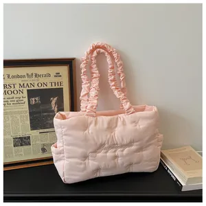 Detail of pink quilted nylon tote featuring bow embroidery and ruched strap design