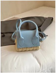 Detailed view of mini light blue leather and straw woven handbag on a white fabric surface