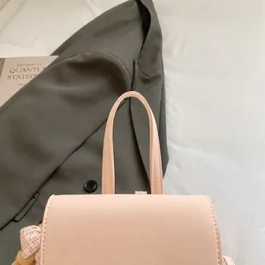 Primer plano del asa de una mochila de cuero sintético rosa con costuras detalladas