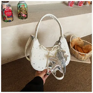 Detail van witte hobo-tas met sterrenprint en metalen bedeltje op getextureerd kunstleer