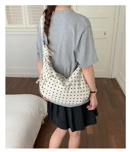 Close-up of a white polka dot shoulder bag featuring a decorative side bow on a model