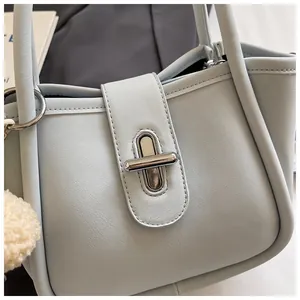 Detail of light blue lychee pattern bucket bag with silver metal twist lock and plush charm