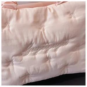 Detailed close-up of quilted nylon fabric with embroidered bows and brand logo
