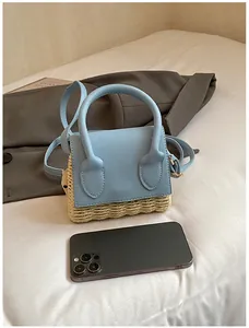 Detail view of mini straw crossbody bag in sky blue leather on white fabric background