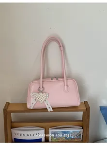 Détail du sac Boston rose avec pendentif coeur en dentelle de perles et bandoulières