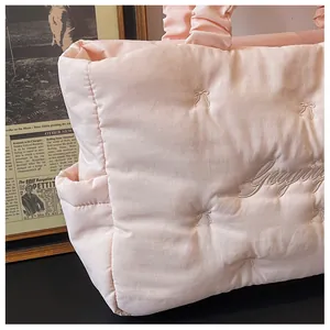 Close-up of pink puffy quilted tote bag with bow embroidery and side pocket detail