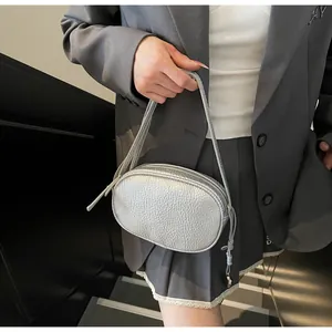 Detail of silver oval pillow bag with metallic pleated texture and tassel zipper pull