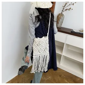Detailed close-up of white woven cotton shoulder bag with fringe tassels and hollow patterns