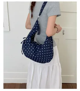 Close-up of navy blue polka dot hobo bag with a sweet bow tie detail on side
