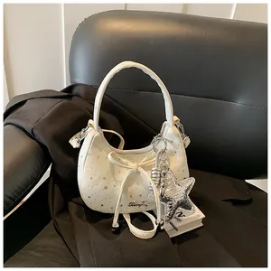 Detail van witte maanvormige tas met sterrenprint en zilveren sterrenhangertje