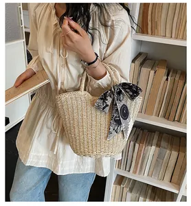 Close-up of beige straw tote bag with a vintage printed silk scarf on handle