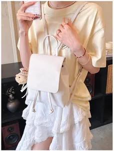 Close-up of a white PU leather mini backpack featuring a drawstring and bear charm