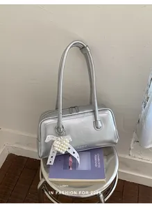 Gros plan d'un sac à main argenté métallisé avec breloque cœur perlé sur un livre