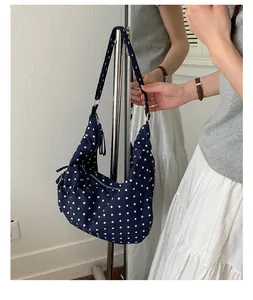 Mirror reflection showing side and front view of navy polka dot crescent shoulder bag