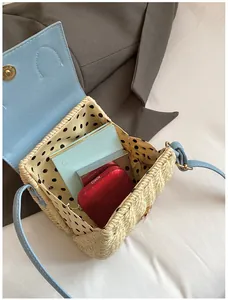 Detail view of woven straw crossbody bag with light blue leather flap and polka dot lining