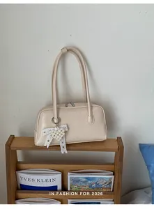 Détail du sac à bandoulière crème avec nœud en dentelle et pendentif cœur en perles
