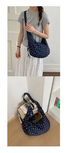 Navy blue polka dot shoulder bag with adjustable drawstring detail on books