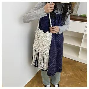 Detailed macro view of beige handmade woven cotton bag featuring bohemian tassel fringe