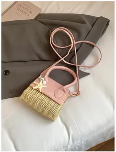 Detail of pink straw mini bag featuring starfish charms and leather handle with strap