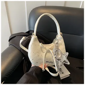 Detail van witte maanvormige tas met zilveren sterren, strik en metalen sterhanger