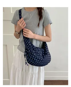 Close-up of blue polka dot shoulder bag with ruffled drawstring design on a female model