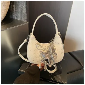 Detail van witte halve maan tas met strik, sterrenprint en glinsterende sterhanger