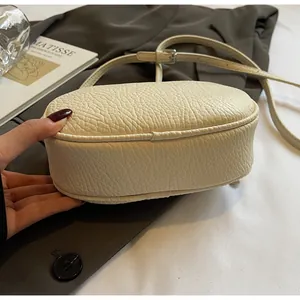 Detailed macro view of cream-colored pillow bag with lychee grain texture and stitching