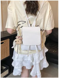 Detail of white PU leather backpack featuring a cute brown plush bear charm pendant