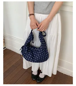 Detail of navy blue polka dot crescent shoulder bag with metallic zipper and knot decor