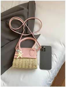 Detailed top view of a mini pink straw handbag with ocean charms and phone for size reference