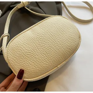 Macro shot of beige litchi grain leather texture and fine stitching on the crossbody bag