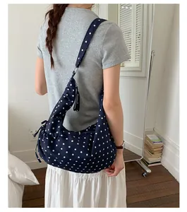 Detail view of navy blue polka dot shoulder bag with side drawstring and tassel zipper